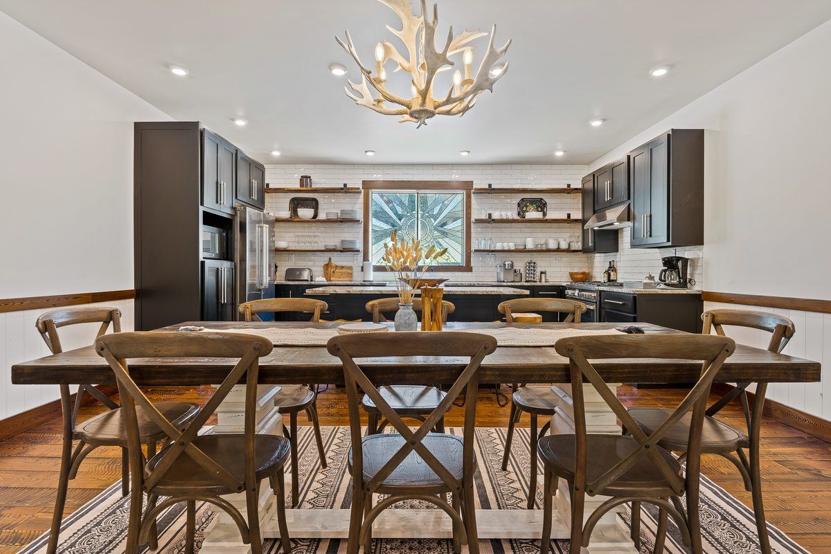 Long dining table under an antler chandelier