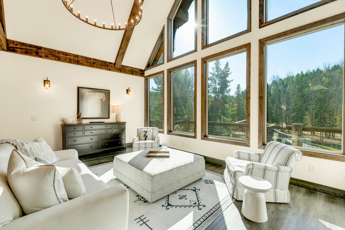 Timber-framed great room with tall windows to the pines