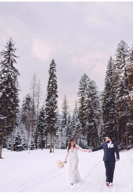 A couple walking through snow among the pines in winter