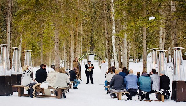 A winter ceremony in the snow, guests seated between patio heaters